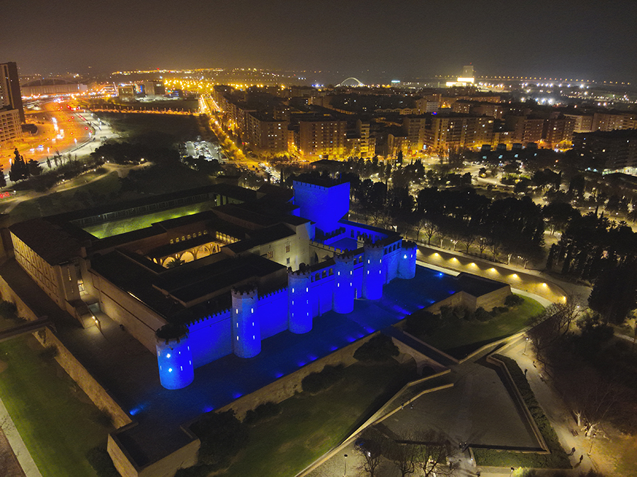 Plano aéreo de edificio de Zaragoza iluminado con el color azul de la Policía Nacional.
